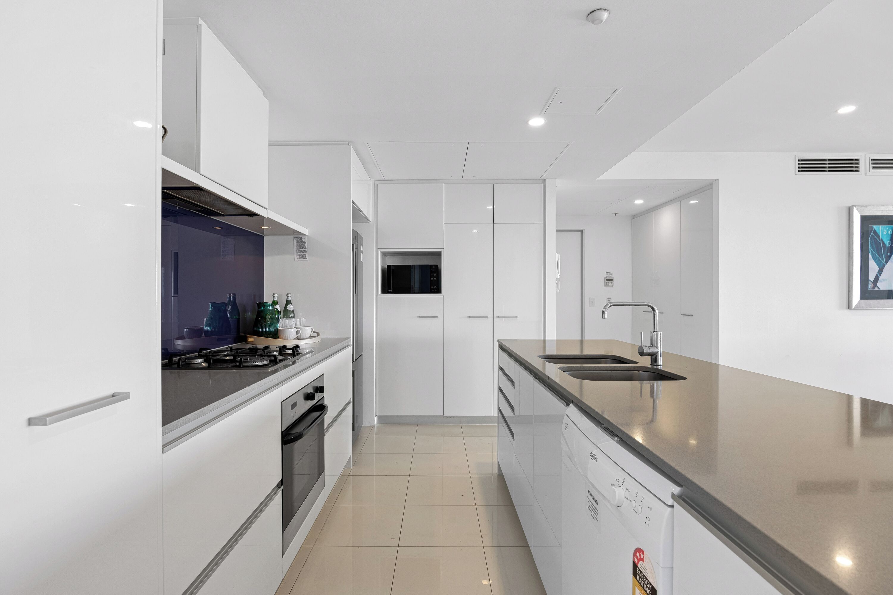 A modern kitchen with white cabinetry, a stainless steel sink, and a dishwasher.