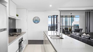 Una cocina moderna con una isla central, electrodomésticos integrados y vistas a la ciudad a través de amplios ventanales.