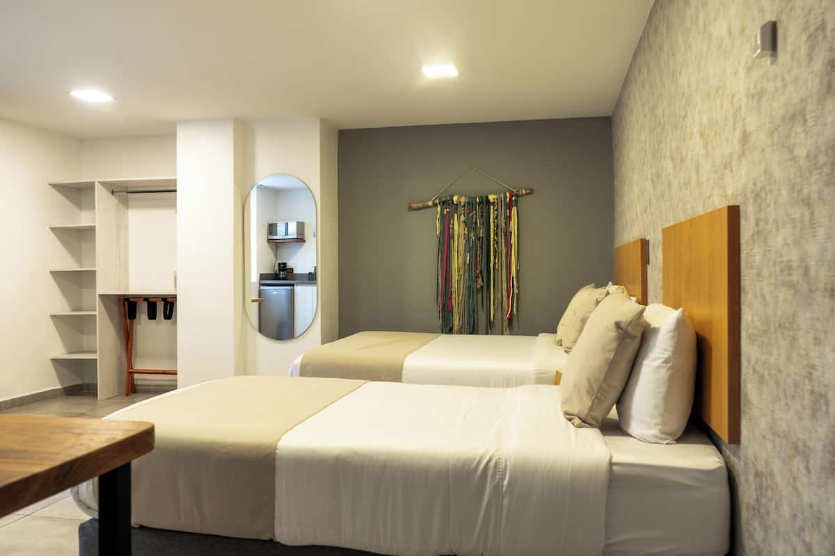 Une chambre d’hôtel avec deux lits, une table en bois, une armoire et un miroir.
