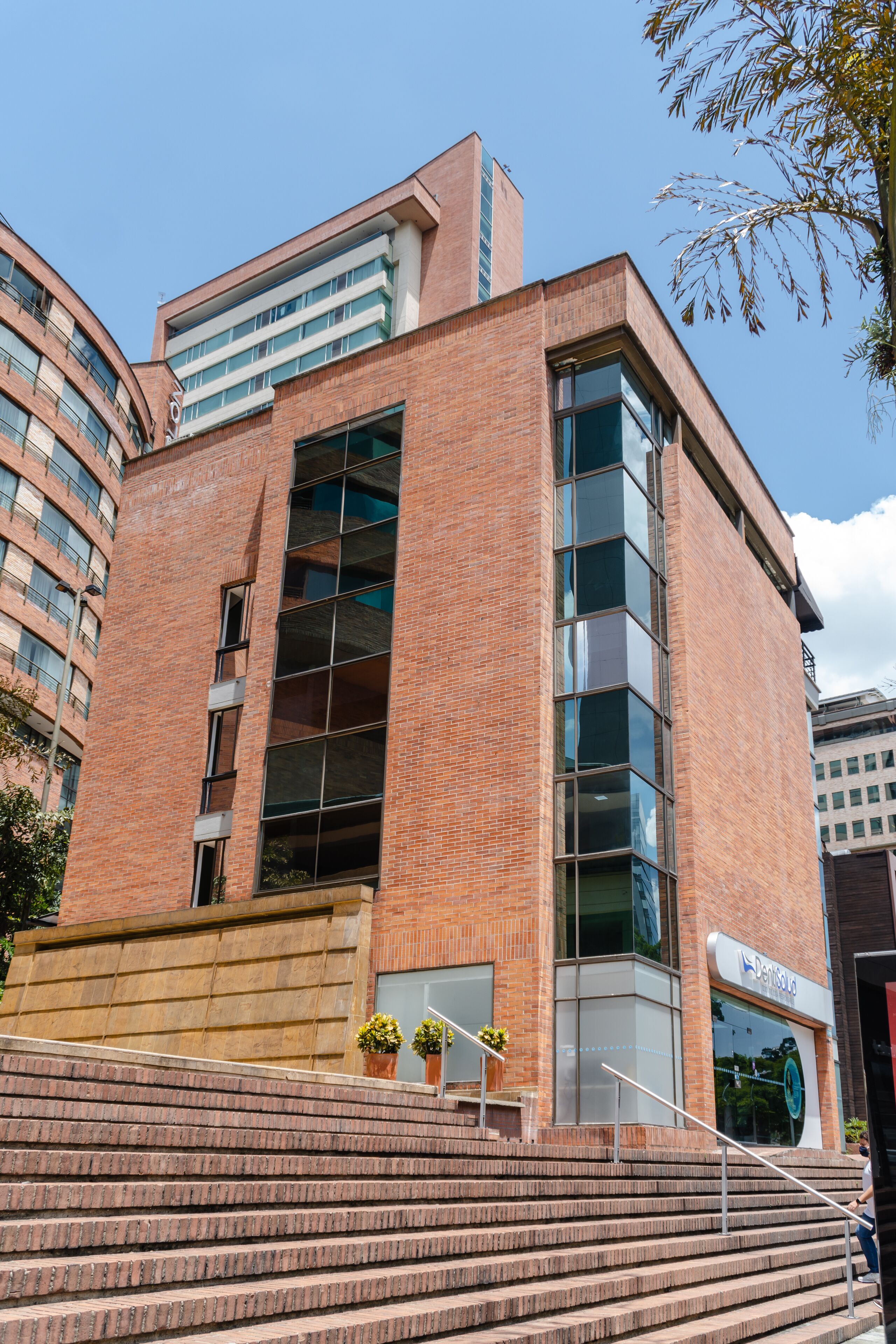 Un edificio moderno con fachada de ladrillo, ventanas amplias y una escalera que lleva a la entrada.