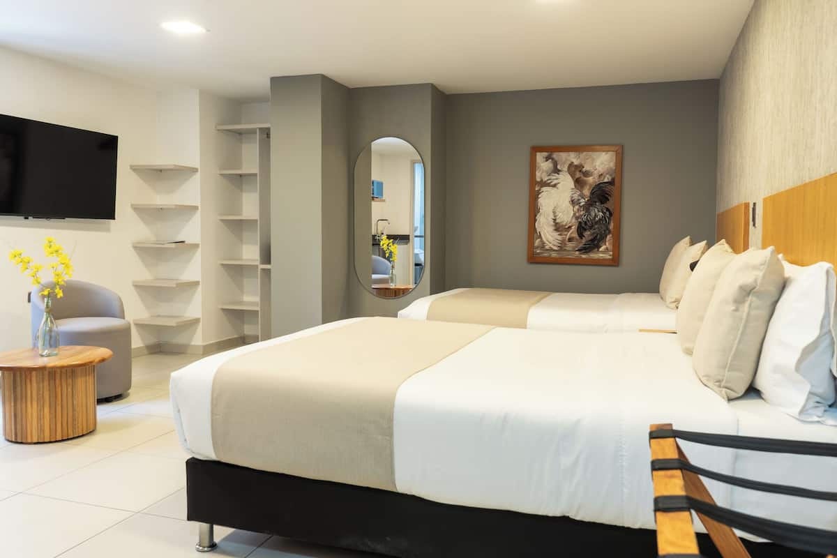 Une chambre d’hôtel moderne avec deux lits, un téléviseur à écran plat, un miroir et un tableau au mur.