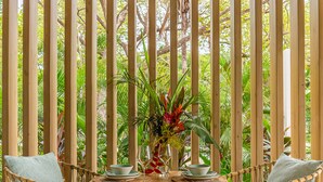 A wooden pergola with a round table and two chairs, surrounded by lush greenery. - Casa Eos - prime location property (Santa Teresa de Cobano)