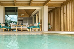 Un espace aménagé au bord de la piscine, avec des meubles en bois et un ventilateur de plafond.