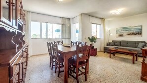 Un amplio salón con una mesa de comedor de madera y sillas, un sofá y un cuadro en la pared.