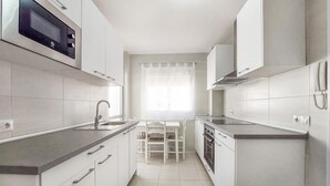 Una cocina moderna con armarios blancos, microondas integrado y un comedor con mesa y sillas.
