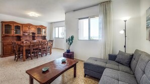 Una sala de estar con una mesa de comedor de madera, un sofá gris y un mueble de madera.
