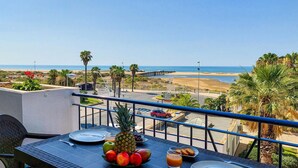 Un balcón con una mesa dispuesta para el desayuno, con vistas a una playa y al océano.