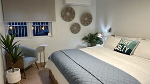 Ein Schlafzimmer mit einem Bett, einem kleinen Tisch, einem Stuhl und einer Topfpflanze.