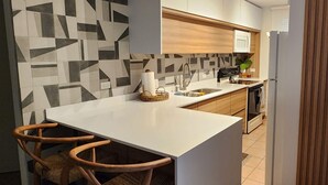 Eine moderne Küche mit weißer Arbeitsplatte, Holzschränken und einer geometrischen Spritzschutzwand.