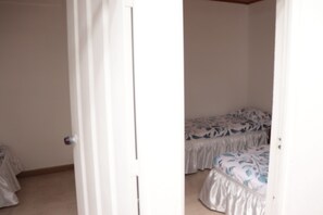 A room with two beds, one with a floral bedspread and another with a plain cover.