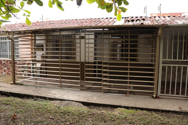 A metal gate with a tiled roof and a brick wall in the background.