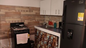 Une cuisine équipée d’une cuisinière, d’un évier et d’un r éfrigérateur.