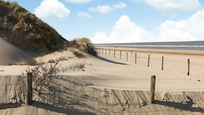 A sandy beach with a wooden fence and dunes in the background. - Stunning home in Noordwijk with WiFi (Noordwijk)