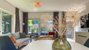 A modern living room with a glass vase on a white table, a sofa, and a dining area. - Stunning home in Noordwijk with WiFi (Noordwijk)