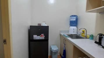 Een koelkast, een waterkoker, kookgerei, borden en bestek