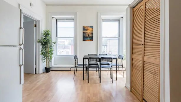 Un comedor con una mesa y sillas, una planta en maceta y un cuadro en la pared.