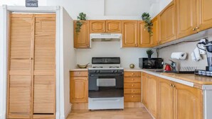 Cocina compacta con gabinetes de madera, horno y microondas.