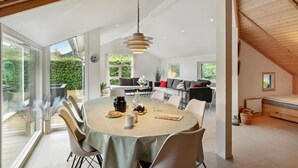 A modern dining area with a round table, chairs, and a hanging light fixture.