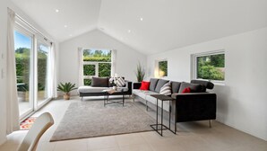 A spacious living room with a high ceiling, large windows, a sofa set, and a coffee table.