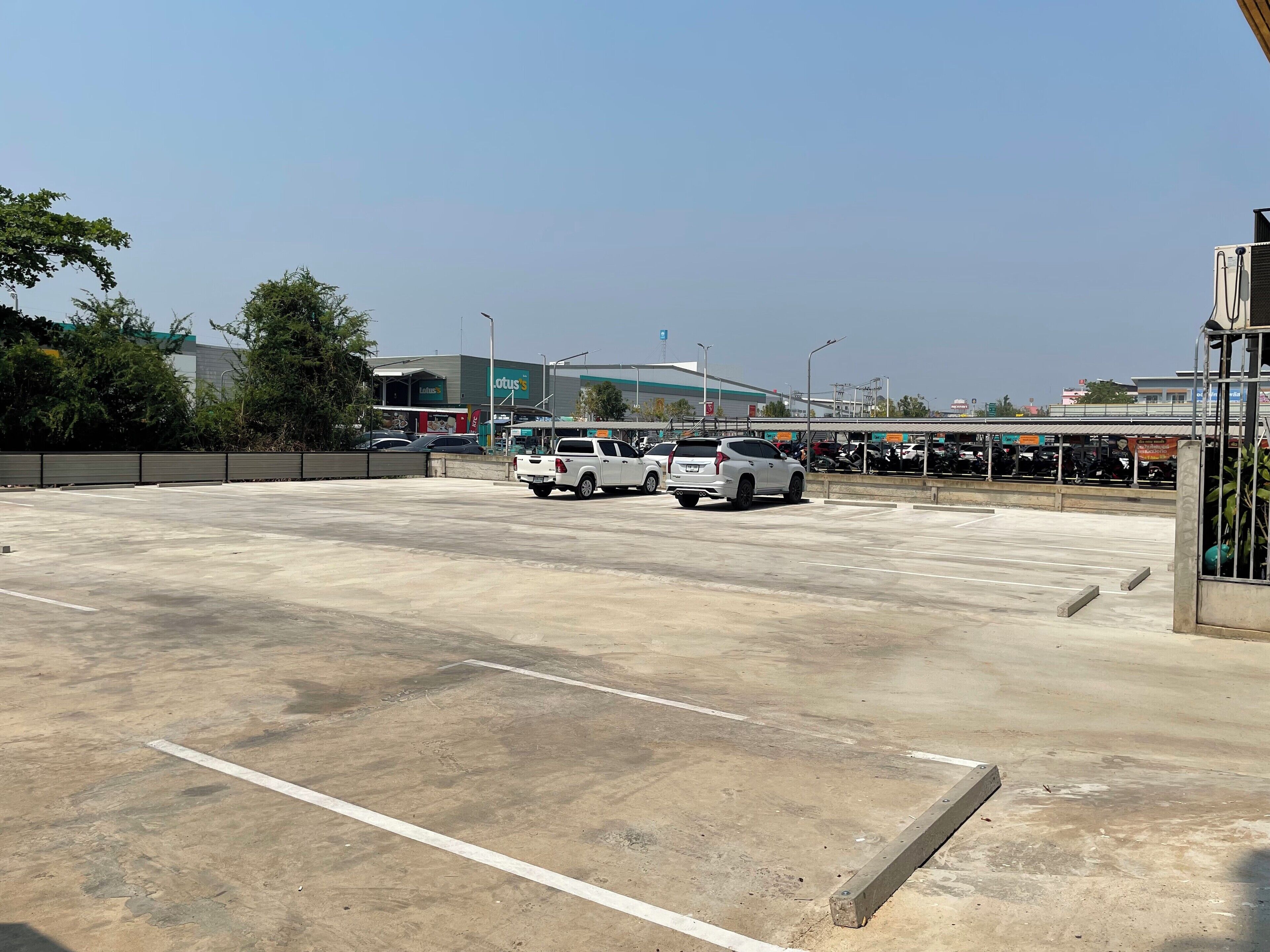 Un estacionamiento con varios coches, una gasolinera y un edificio con un letrero que dice "Lotus".