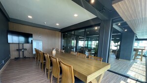 A conference room with a long wooden table, chairs, a whiteboard, and a TV. - The Bedrooms Maeklong Service Apartment (Samut Songkhram)