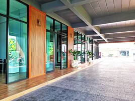 A modern building with large glass windows, a wooden panel accent, and a tiled floor.
