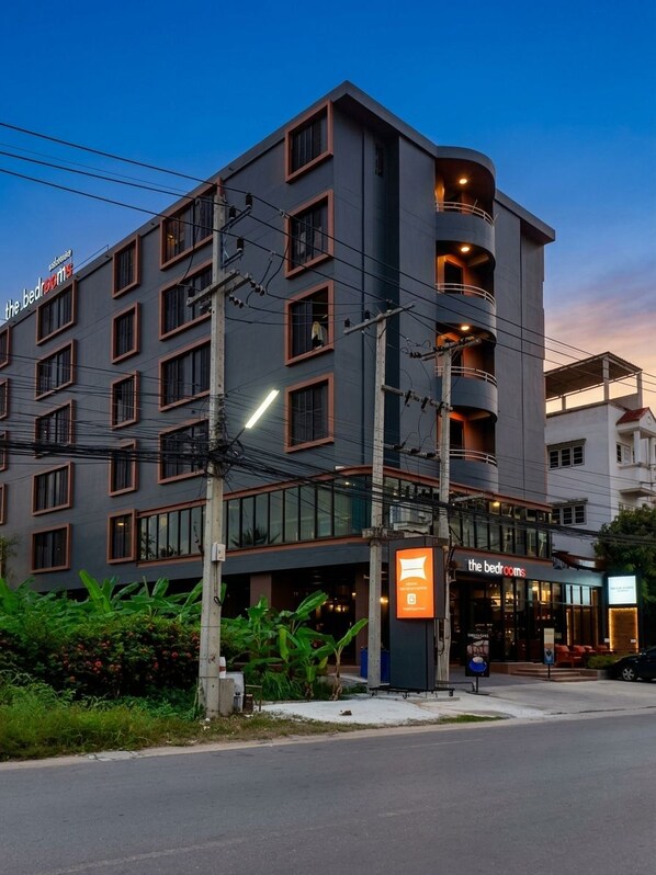 Un hotel de varios pisos con diseño moderno, que cuenta con balcones y una señalización llamativa que indica 'the bedrooms' en la planta baja.