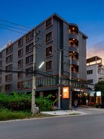 Un hotel de varios pisos con diseño moderno, que cuenta con balcones y una señalización llamativa que indica 'the bedrooms' en la planta baja.