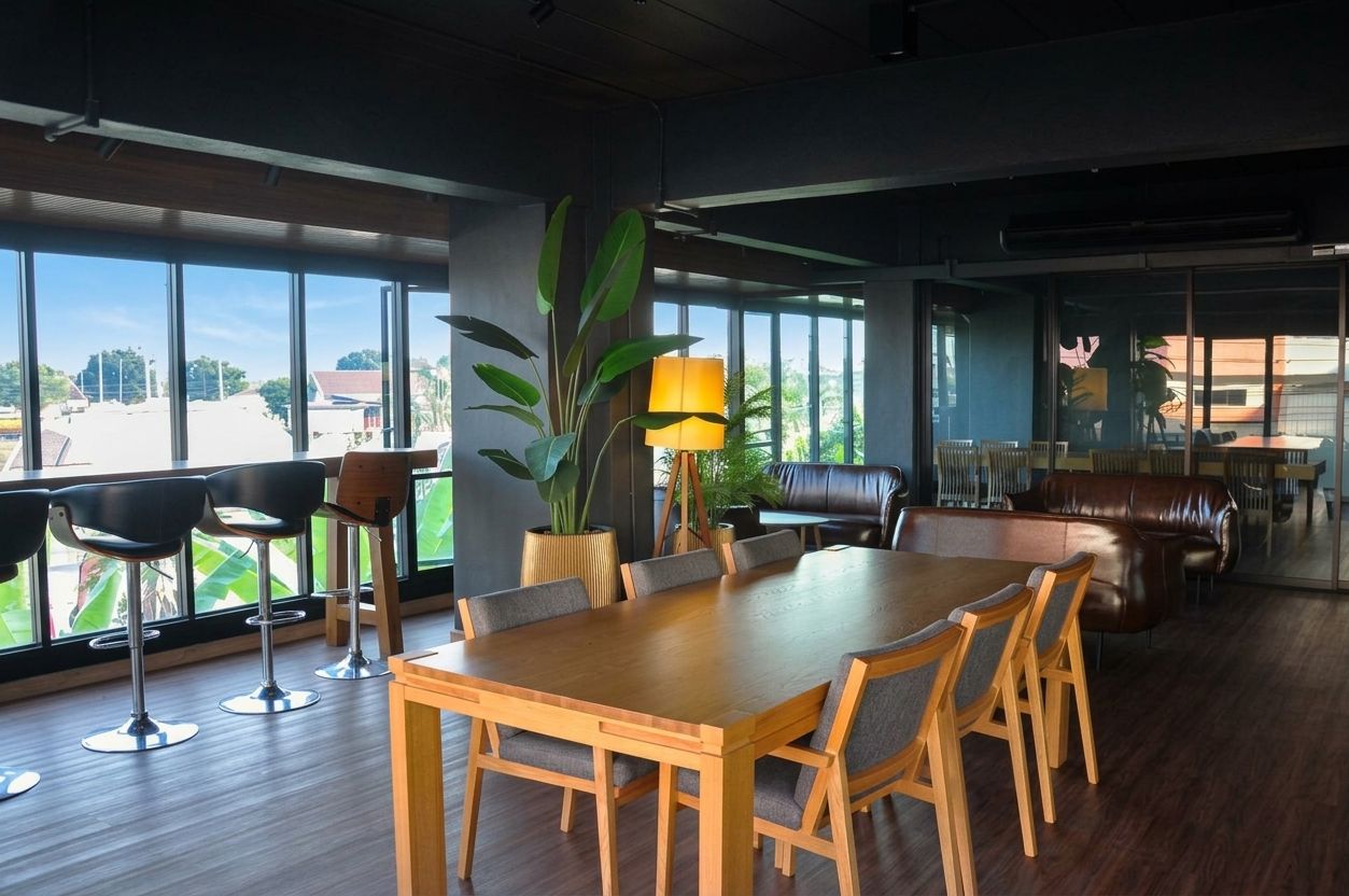 A spacious dining area with a large wooden table and chairs, surrounded by large windows offering a view of the outdoors.
