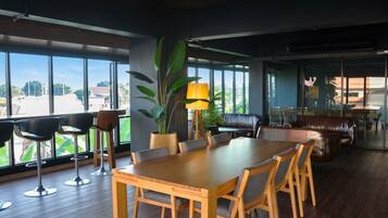 A spacious dining area with a large wooden table and chairs, surrounded by large windows offering a view of the outdoors.