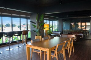 Un comedor amplio con una gran mesa de madera y sillas, rodeado de ventanas que ofrecen vistas al exterior.