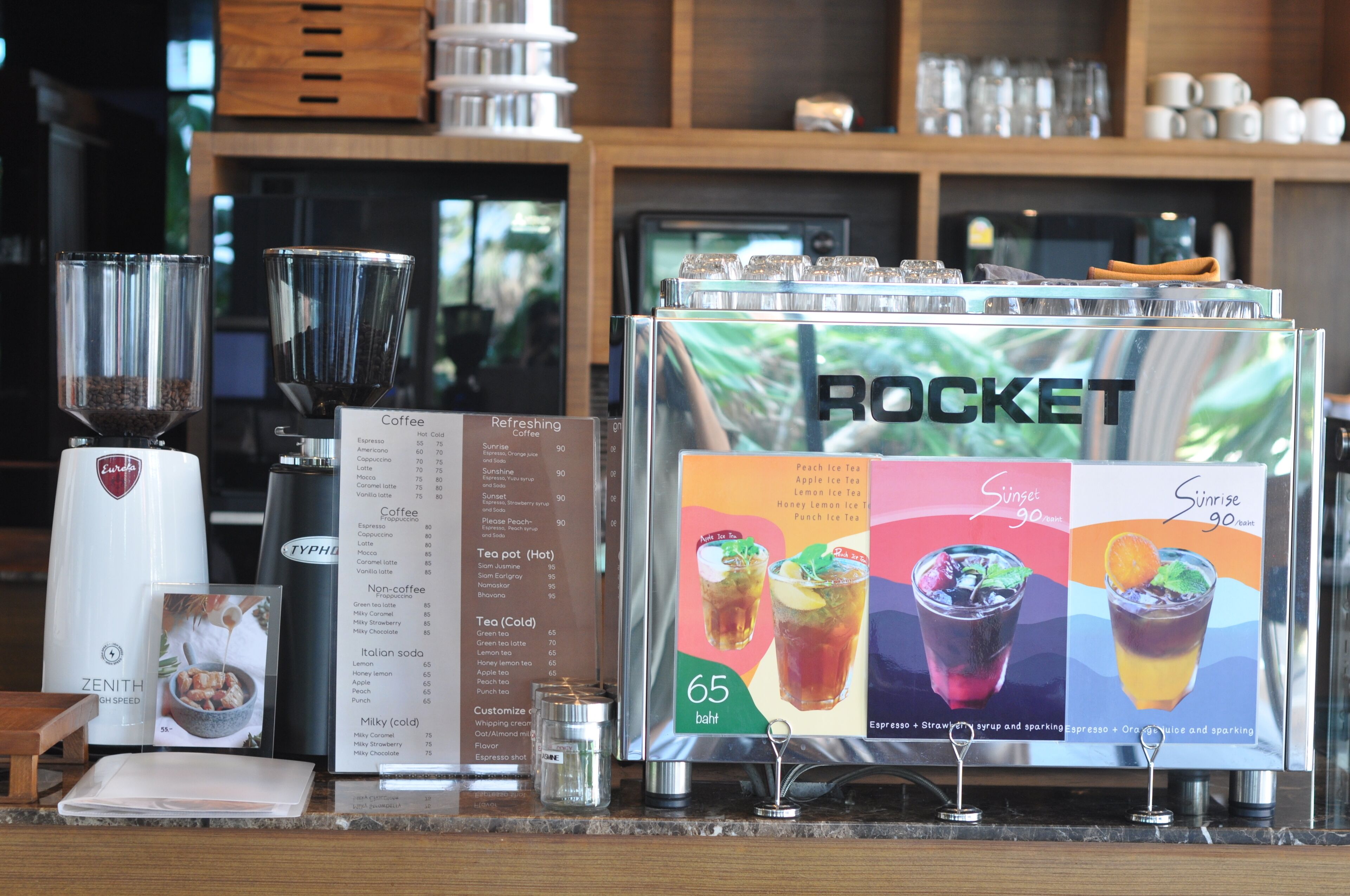 A coffee station with a menu board, coffee machines, and a display of iced tea options.