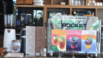 A coffee station with a menu board, coffee machines, and a display of iced tea options.