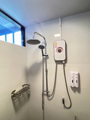 Een douche met een handdouche en een bedieningspaneel aan de muur.