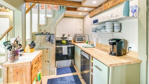A compact kitchen with wooden beams, a built-in oven, a microwave, and a coffee maker. - Historic Winter Harbor Cottage w/ Waterfront Views (Winter Harbor)