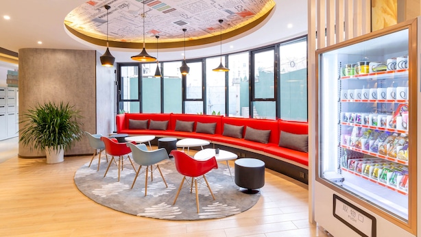 A modern lounge area with a red sofa, round tables, and chairs, a vending machine, and a ceiling with a circular design. - Ibis Xi an Shaanxi Province People Hospital Hotel (Xi'an)
