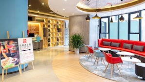 A modern interior with a red sofa, blue chairs, and a large potted plant. - Ibis Xi an Shaanxi Province People Hospital Hotel (Xi'an)
