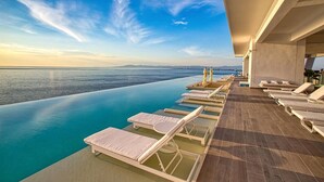 A poolside area with lounge chairs and a view of the sea.