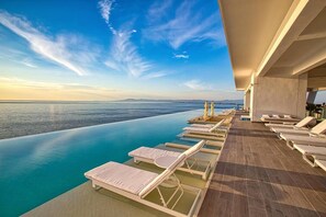 A poolside area with lounge chairs and a view of the sea.