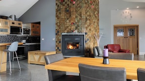 Una cocina moderna con chimenea de pared de piedra, muebles de madera y un comedor.