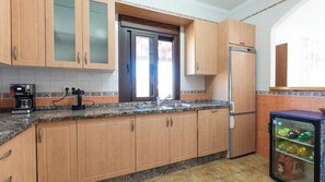 A kitchen with wooden cabinets, a refrigerator, a coffee maker, and a beverage cooler. - Villa Medina Torrox by Ruralidays (Málaga)