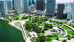 A high-rise urban area with modern skyscrapers, a waterfront park, and a circular plaza. - The Romantic Bird House | A Storybook Garden Retreat (Homestead)