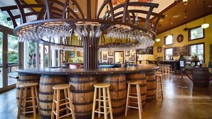 A bar area with wooden barrels, stools, and a central chandelier. - The Romantic Bird House | A Storybook Garden Retreat (Homestead)