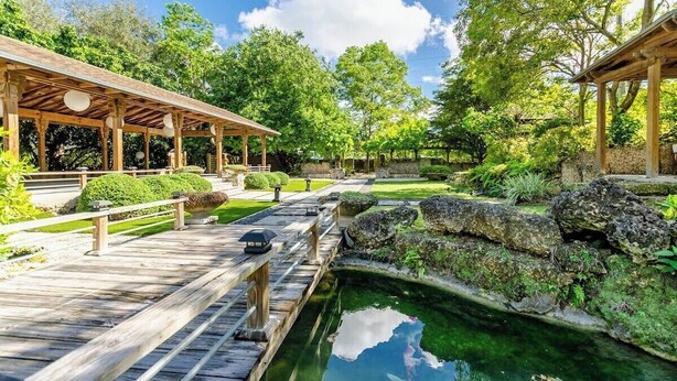 A wooden deck with a pond, surrounded by greenery and a gazebo. - The Romantic Bird House | A Storybook Garden Retreat (Homestead)