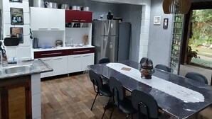 A modern kitchen with a dining area, stainless steel appliances, and a large window. - Rancho Paraíso Piscina Aquecida Mairiporã/nazaré PTA (Mairiporã)