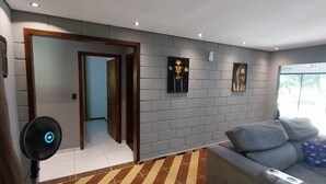 A modern living room with a grey sofa, a fan, and artwork on the wall. - Rancho Paraíso Piscina Aquecida Mairiporã/nazaré PTA (Mairiporã)
