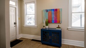 A hallway with a blue cabinet, a colorful abstract painting, and a white door. - *5 Min to WVU*Smart TV*2 Full Kitchen*W/D (Morgantown)