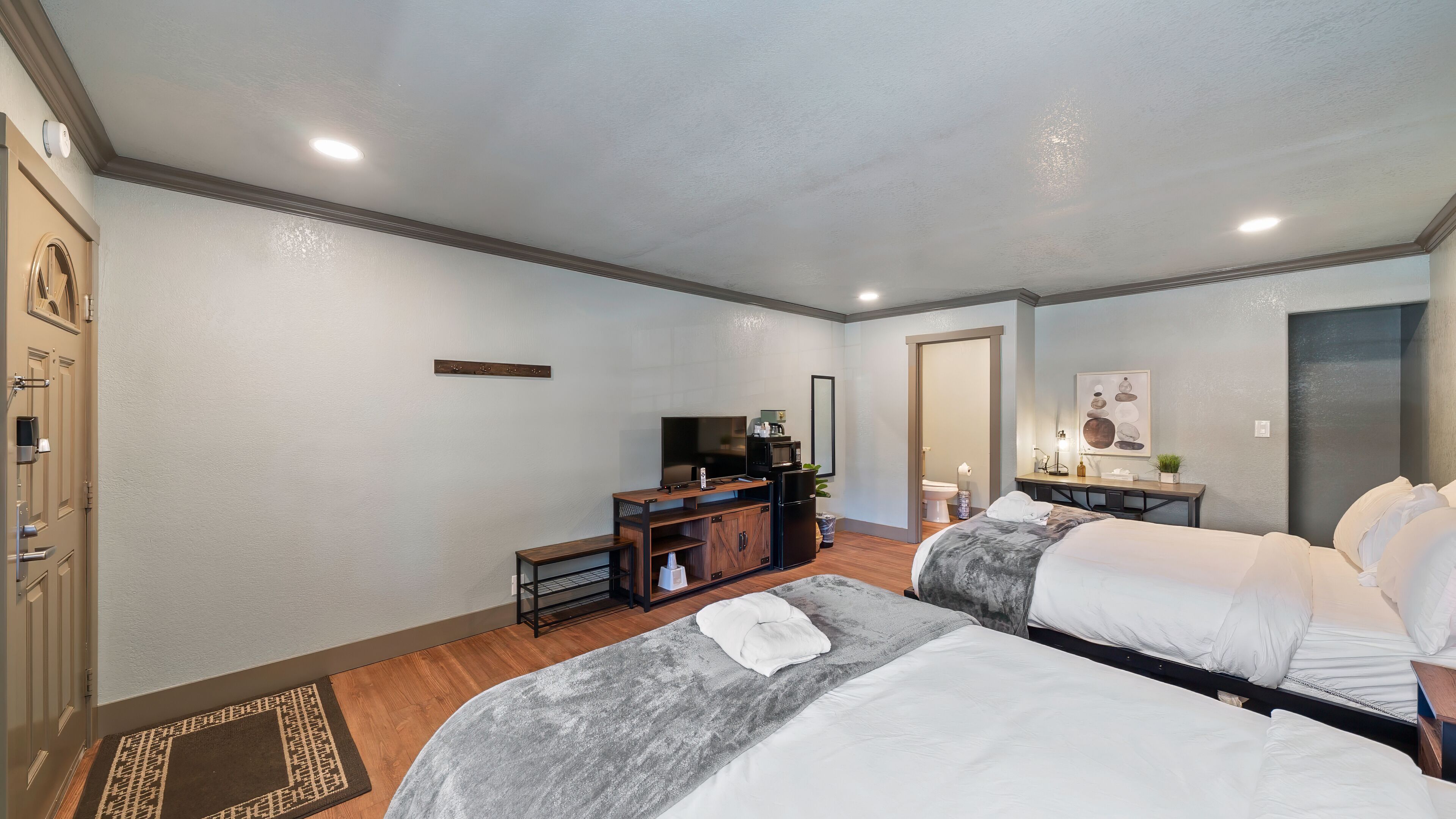 Une chambre d’hôtel avec deux lits, une télévision, un réfrigérateur, un four à micro-ondes et un petit bureau avec une lampe.