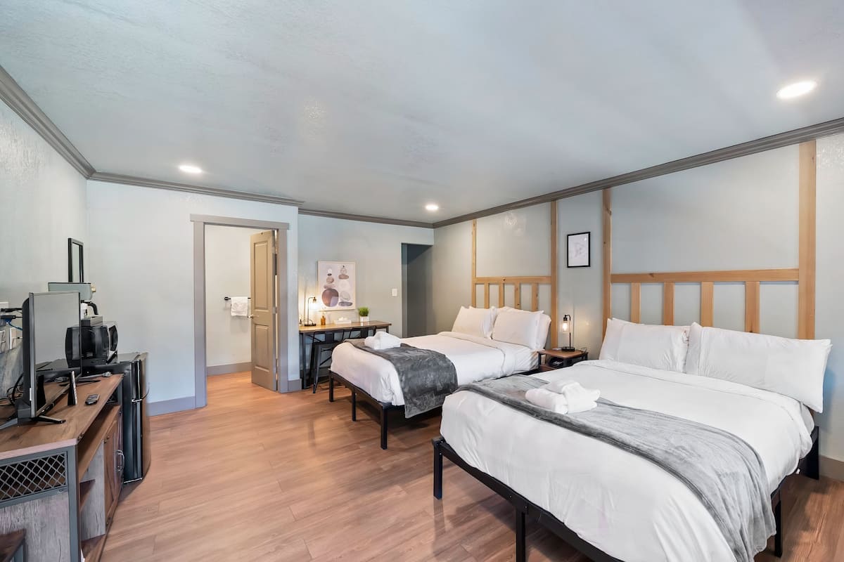A hotel room with two beds, a desk, and a television.