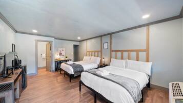 A hotel room with two beds, a desk, and a television.